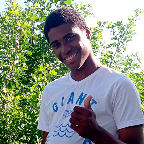 Adolescente de cor negra sorrie faz sinal de positivo com a mão.