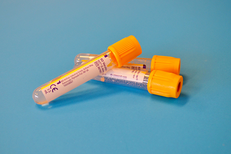 tubo de exame de sangue nas cores branca e laranja.