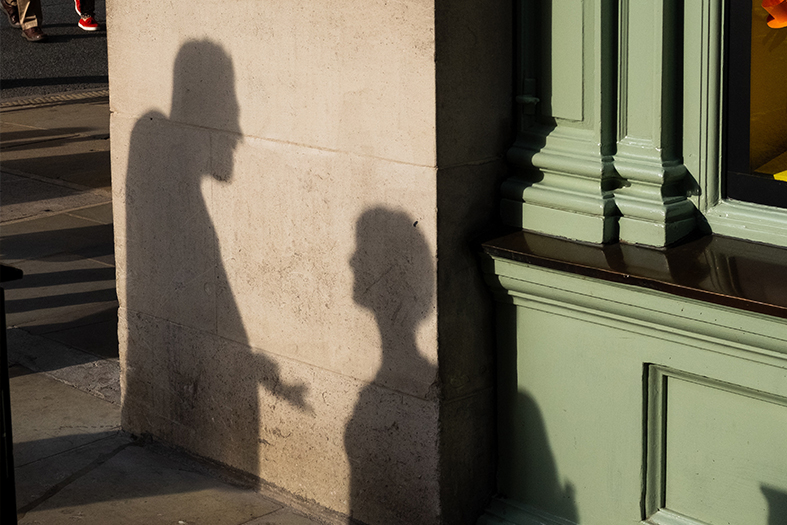 Sombra projetada em um prédio de um casal tendo uma discussão.