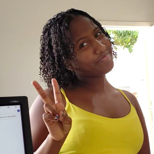 Menina de pele negra fazendo sinal de "v" com os dedos em pose para foto..