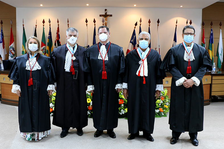 Quatro pessoas usando toga posam para foto.