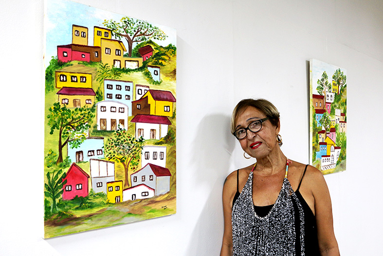 Artista plástica Bety Ruska posando junto a um de seus quadros.