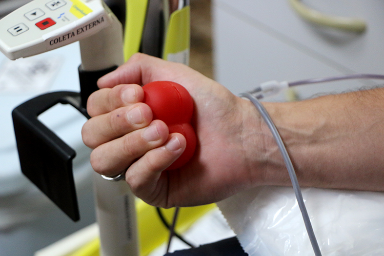 Detalhe de uma pessoa apertando uma bola para facilitar o bombeamento de sangue durante a doação.