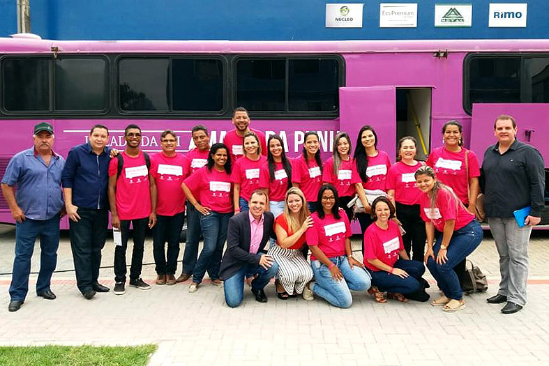 Equipe do Juizado Itinerante da Lei Maria da Penha posa em frente ao "ônibus rosa" em Pancas/ES.