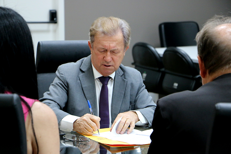 O presidente do TJES, desembargador Fabio Clem, assina documento em seu gabinete.