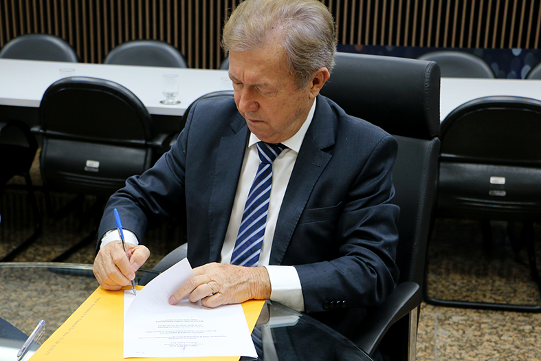 O presidente do TJES, desembargador Fabio Clem, assina documento em seu gabinete.