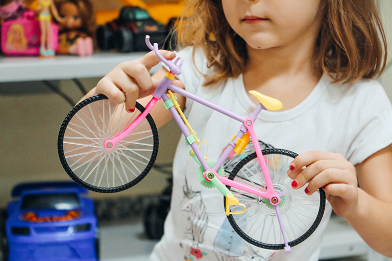 Criança segura bicicleta de brinquedo.