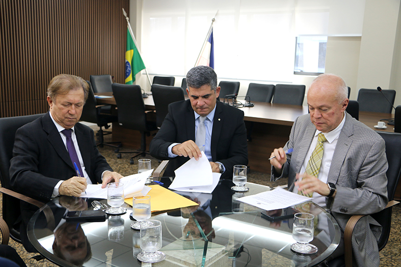 O presidente do TJES, desembargador Fabio Clem, o desembargador Pedro Vals Feu Rosa e o prefeito de Piúma/ES assinam documentos de cooperação.
