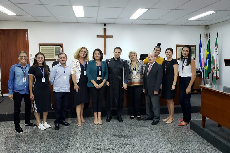 Grupo de pessoas posa para foto dentro de um salão do juri