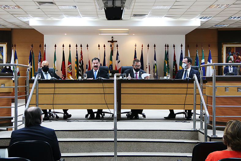 Quatro homens sentado em mesa de honra durante um evento no salão pleno do TJES