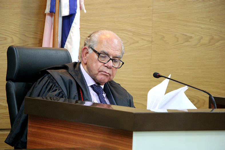 Homem vestindo toga de desembargador revisa alguns papéis.