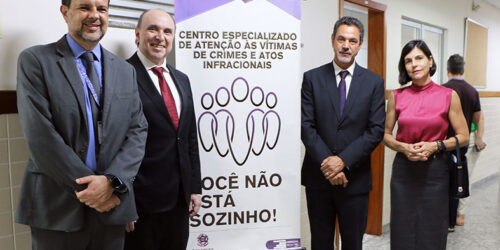 Autoridades do judiciário capixaba posam ao lado de banner com os dizeres "centro especializado de atenção às vítimas de crimes e atos infracionais".
