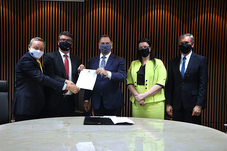 Foto dos componentes da mesa de honra segurando o Termo de Adesão.