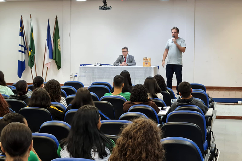 Auditório cheio de crianças e adolescentes que assistem a uma palestra.