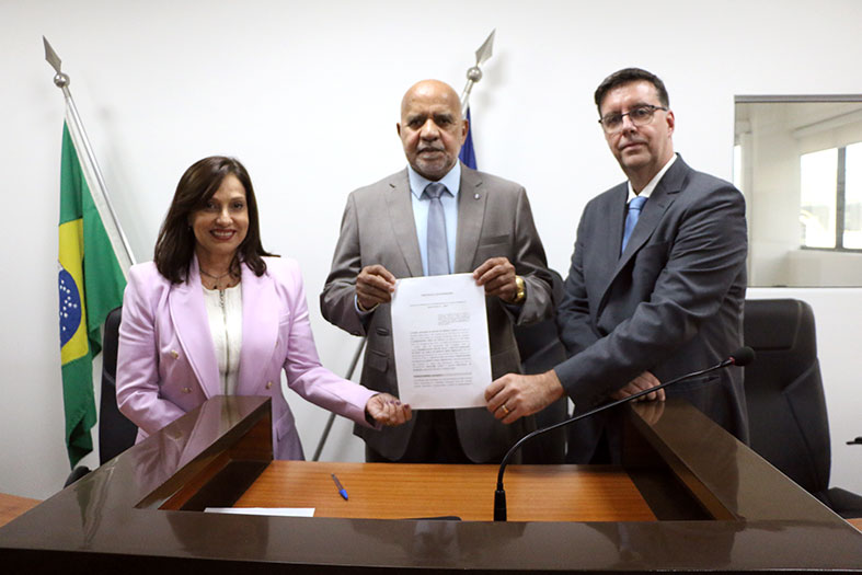 O corregedor-geral da Justiça, desembargador Willian Silva, a presidente do IBDFam-ES, Flavia Brandão Maia Perez e o presidente do Sindicato de Notários e Registradores do Estado do Espírito Santo, Márcio Oliva Romaguera, seguram o protocolo de intenções assinado pelas três entidades.