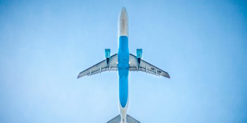 Vista inferior de um avião cruzando um céu azul.