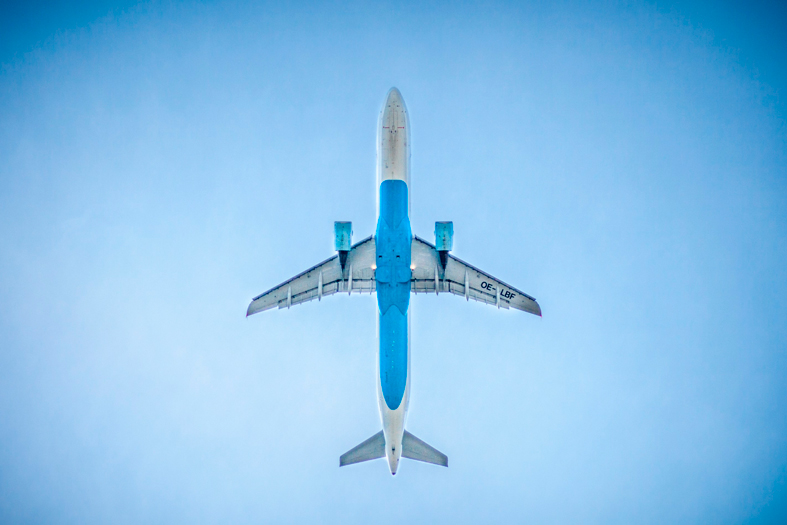 Vista inferior de um avião cruzando um céu azul.