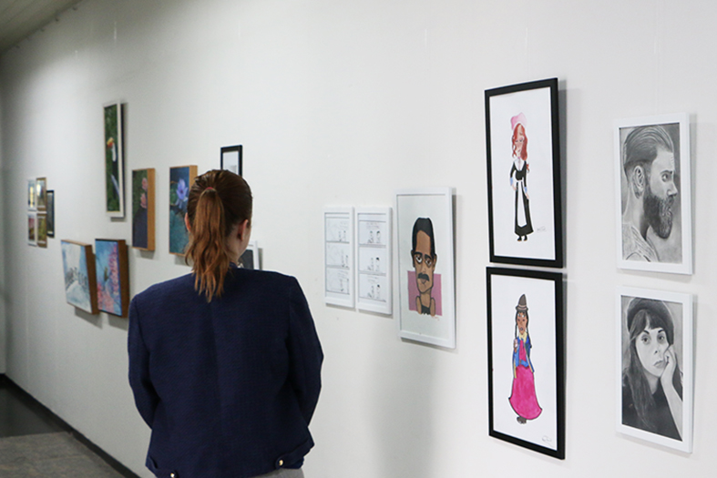 Uma mulher observa uns quadros na exposição