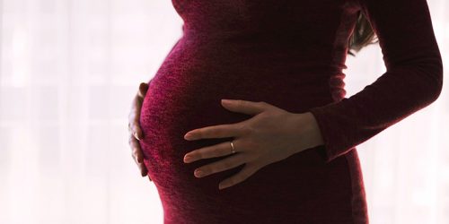 mulher grávida com as mãos repousadas sobre a barriga