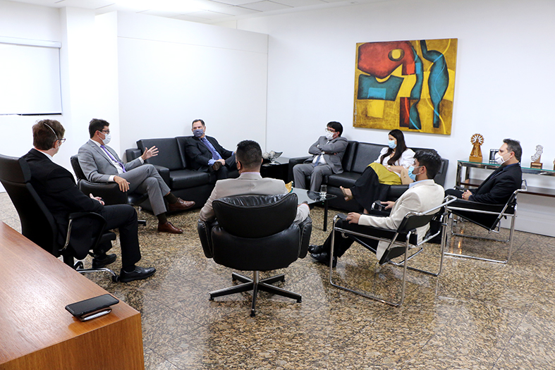 pessoas sentadas em cadeiras reunidas ao redor de uma mesa de centro