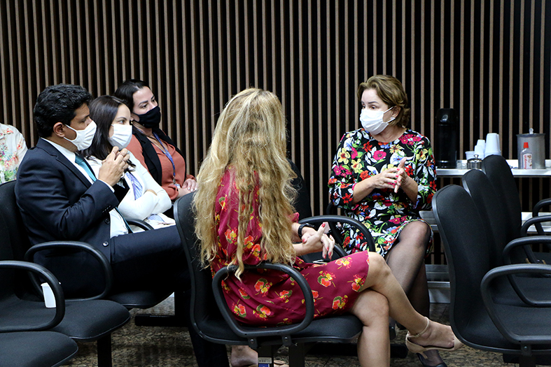 Quatro mulheres e um homem sentados conversando.