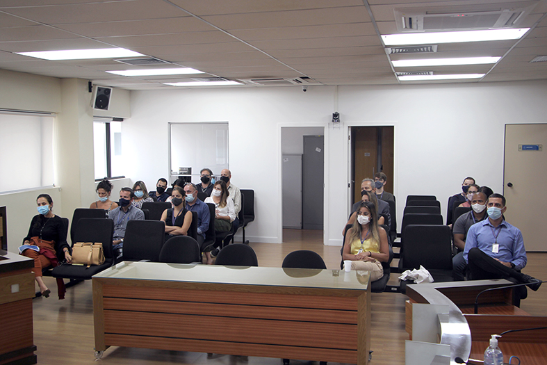 pessoas com máscara e distanciamento social assistem sentadas a uma apresentação de projeto