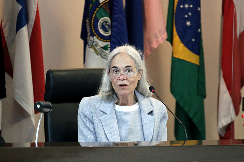 Ministra Maria Thereza Moura, mulher de pele clara, com cabelos de cor branca. Ela está vestindo um blazer na cor cinza claro.