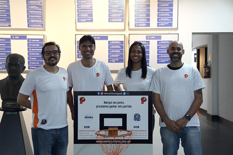 Representantes do instituto peb posam para foto junto à caixa de doações.