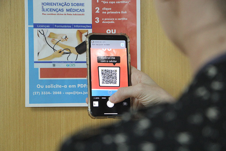 Mulher escaneia o código qr em um cartaz.