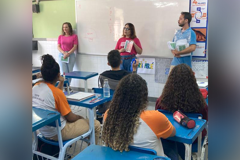 Três servidores do TJES dando palestra em uma escola estadual.