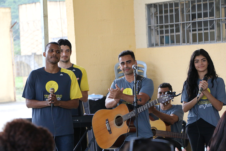 Grupo de pessoas tocando violão e cantando.