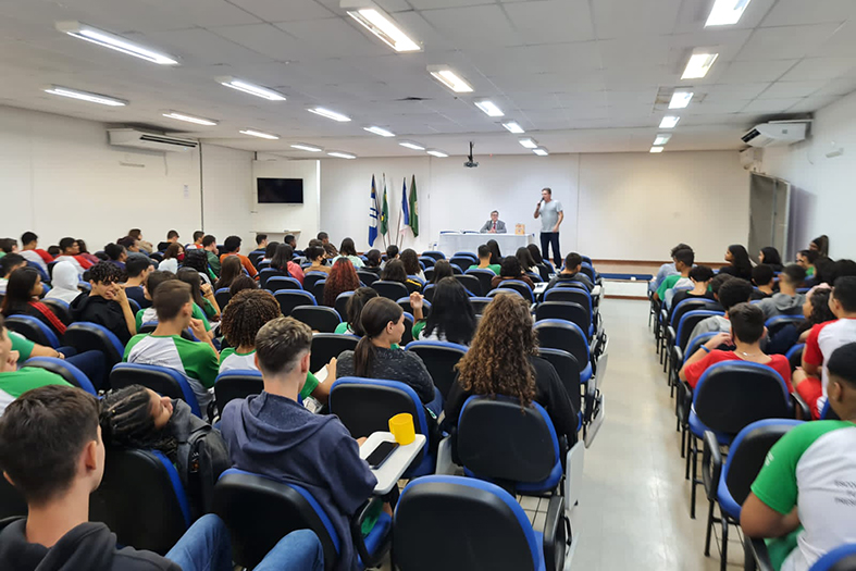 Auditório cheio de crianças e adolescentes que assistem a uma palestra.