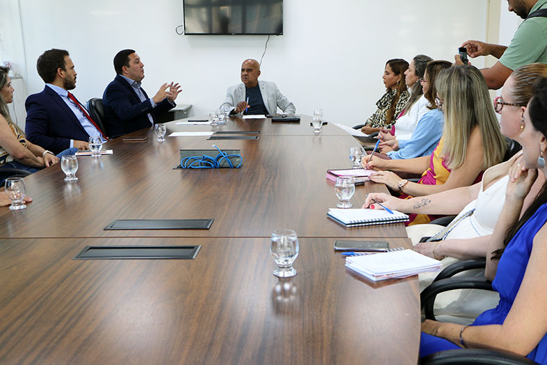 Mesa de reuniões completa com todos os participantes.