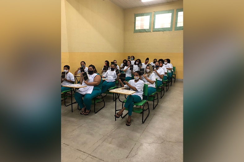 grupo de internas do sistema prisional assiste palestra. Todas afastadas e usando máscara.