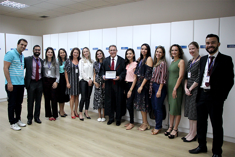 Equipe de servidores e estagiários homenageando o desembargador Carlos Simões.