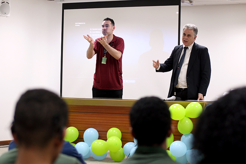 O presidente da Comissão de Acessibilidade e Inclusão do Poder Judiciário Estadual, desembargador Jorge Henrique Valle dos Santos fala ao público enquanto tem suas palavras interpretadas pelo intérprete de libras.