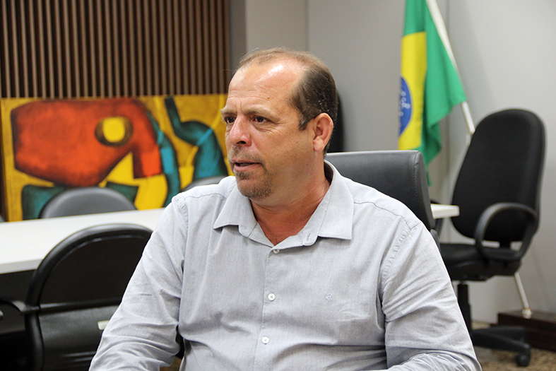 Hélio Cândido, prefeito de Muqui/ES, homem de pele branca, calvo, ele veste camisa de botão na cor cinza-claro.