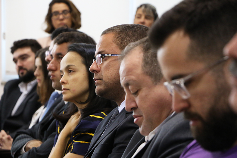 Close em vários rostos de homens e mulheres assistindo a uma audiência