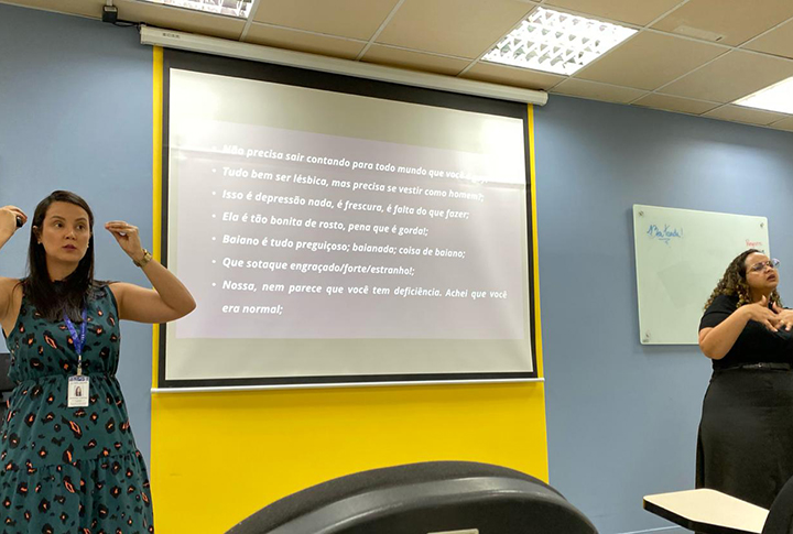 Duas pessoa falando em frente a uma tela de projetor