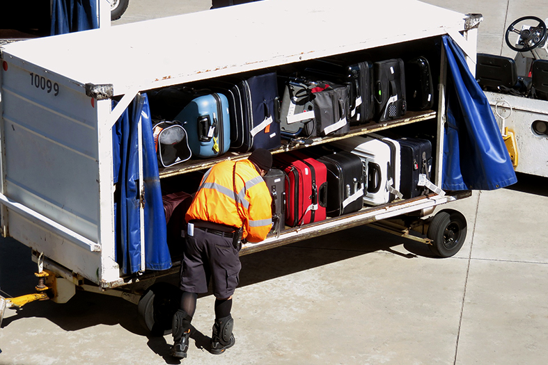 Funcionário de aeroporto transportando malas.