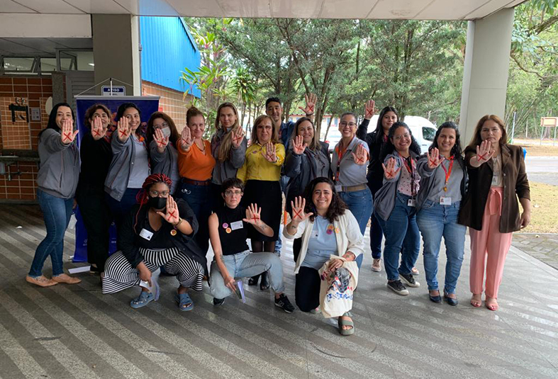 mulheres com x vermelho na mao após palestra em empresa