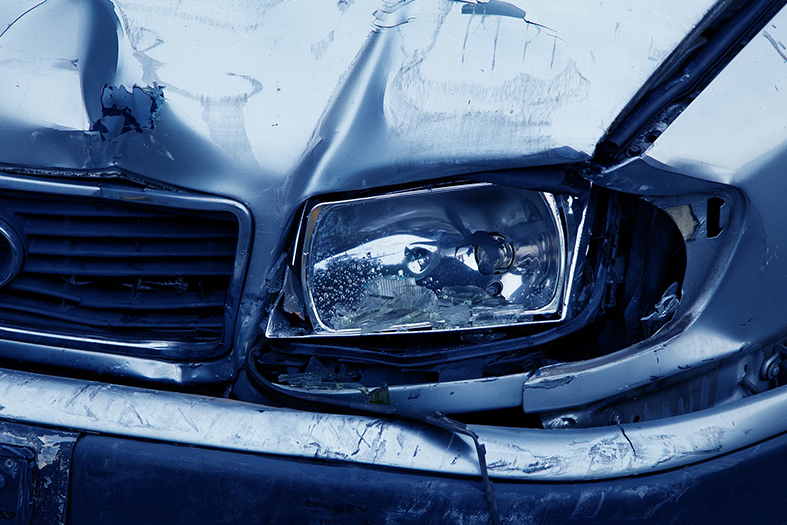 Detalhe de um para choque amassado de carro na cor azul.