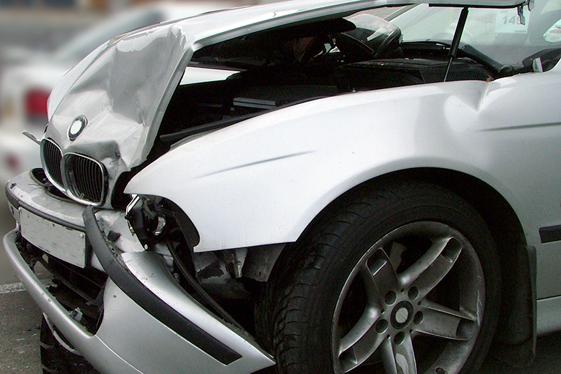 carro na cor branca com o capô do motor e o para-choques amassados