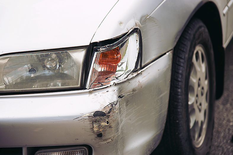 Detalhe de um para choque amassado de carro na cor prata