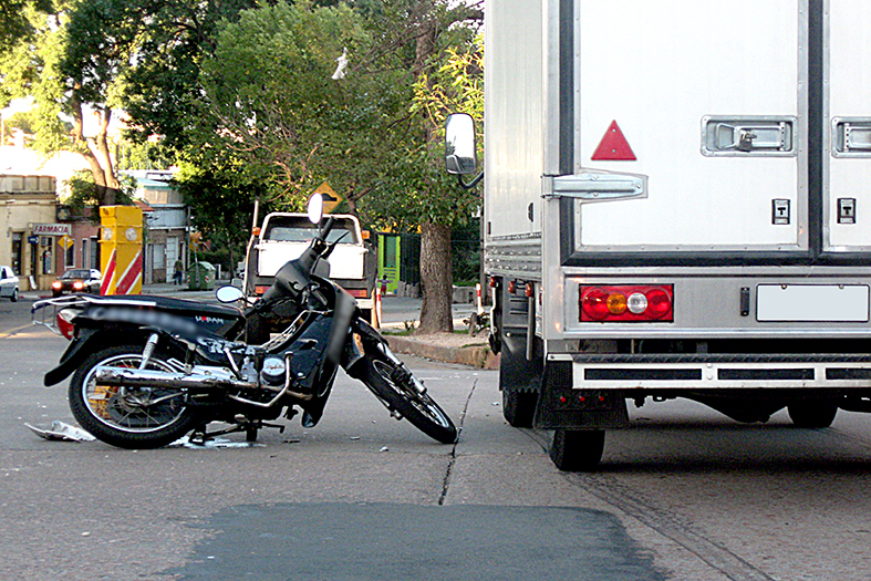 Motocicleta parada ao lado de um caminhas do tipo baú.