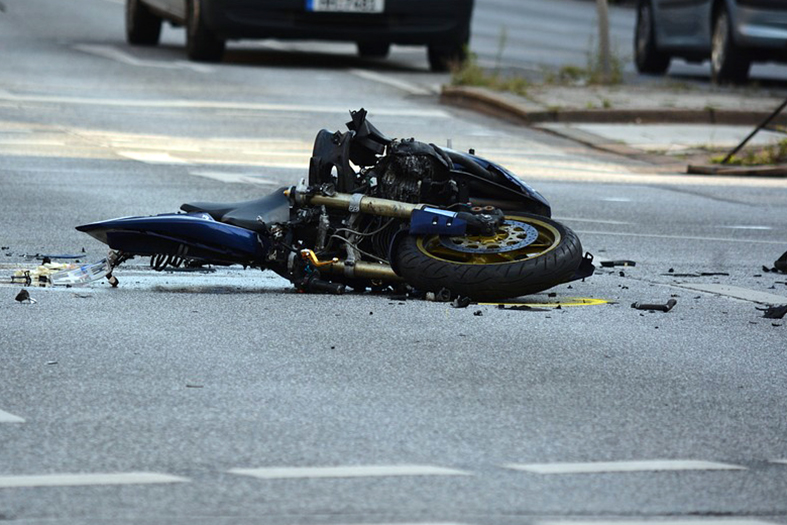 Motocicleta avariada caída no asfalto.