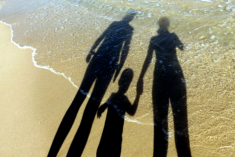 Silhueta de uma família projetada na areia.