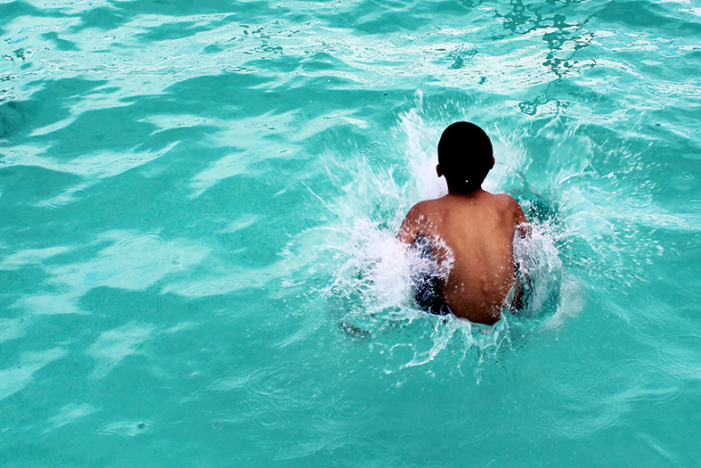 Menino negro mergulhando em água azul truquesa.