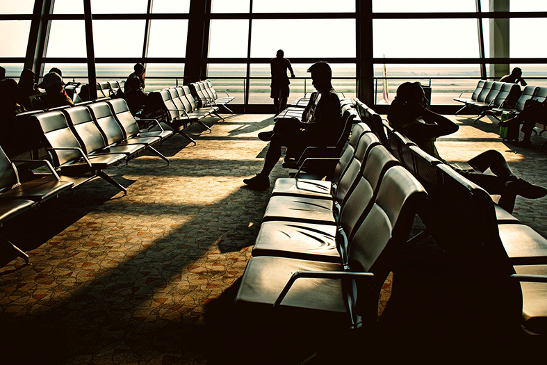 Silhueta de pessoas em saguão de aeroporto.