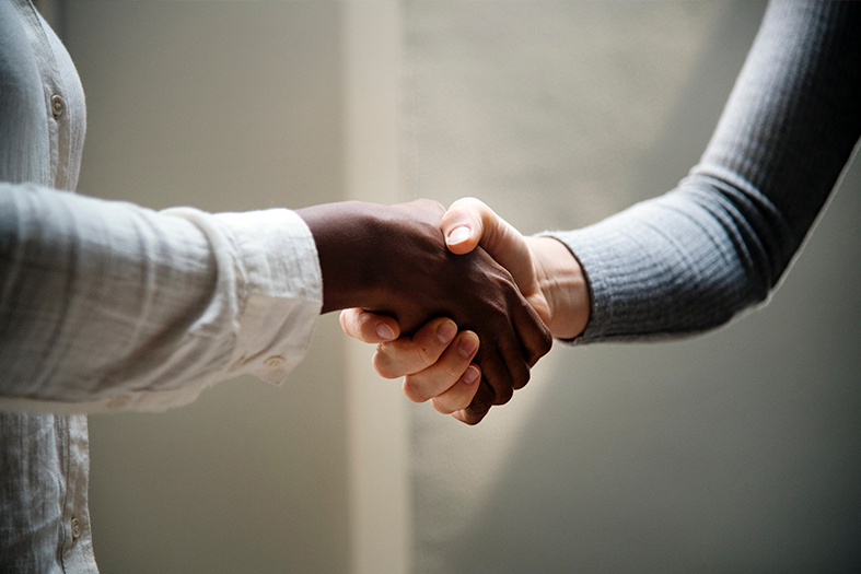 Aperto de mãos entre uma pessoa negra e uma branca.